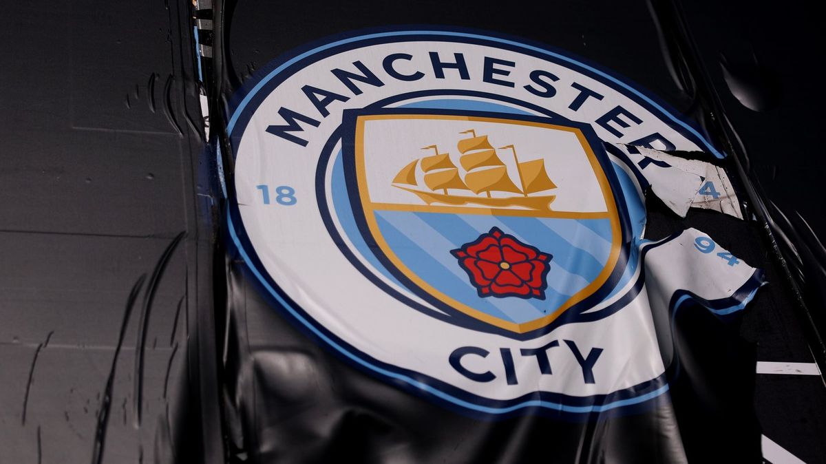 Logo Manchester City dan bola sepak di stadion